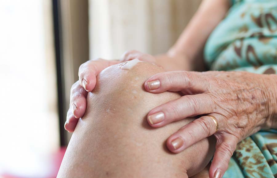 Persona mayor aplicando crema en la pierna