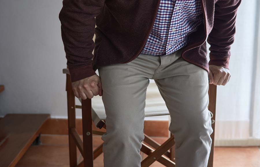 Hombre mayor sentándose en una silla