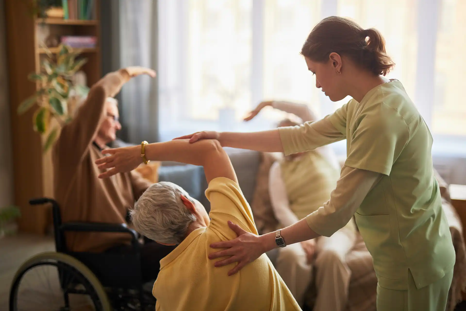 Auxiliar de geriatría haciendo ejercicios con personas mayores